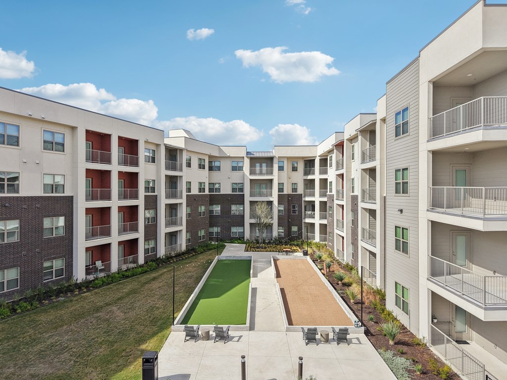 Apartment complex with a green lawn and a small pool.