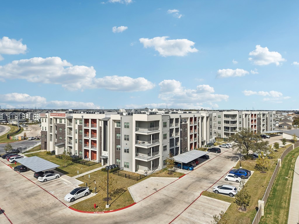 A large apartment complex with a parking lot in front.
