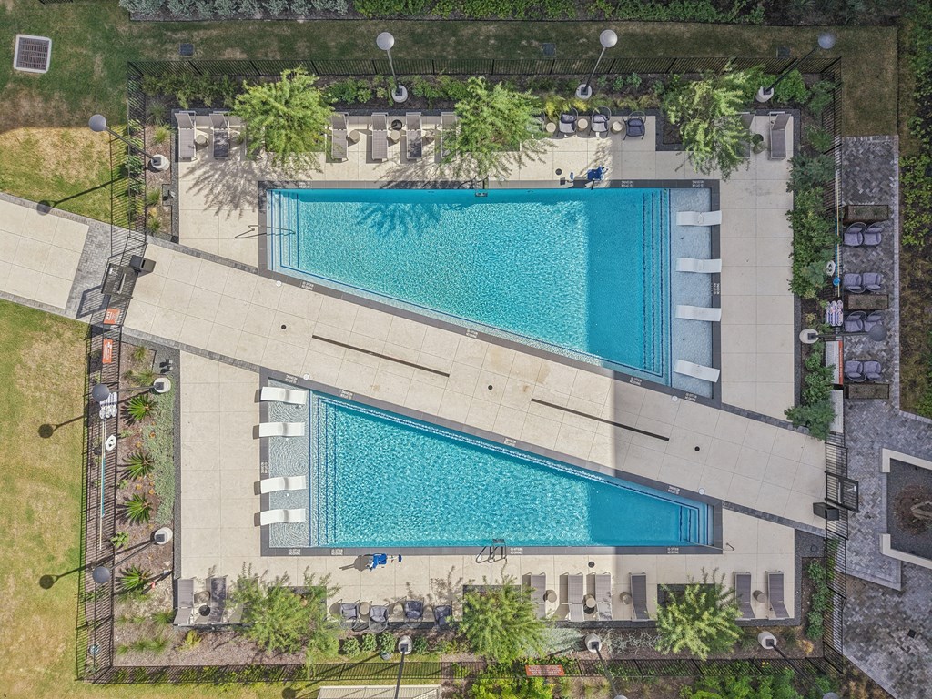 A large swimming pool with a long rectangular pool and a smaller one in front of it.