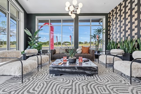 A living room with a black and white patterned rug and a large window with a view of the outdoors.