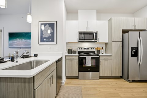 A modern kitchen with a fridge on the right and a sink on the left.