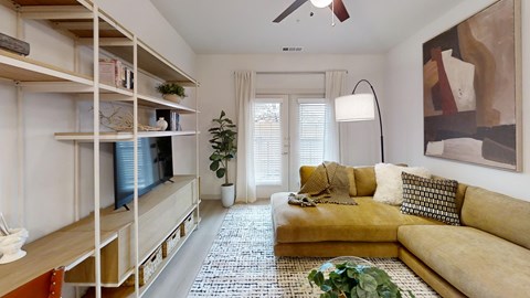 A living room with a yellow couch and a television on a stand.