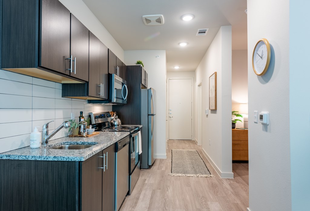 A kitchen with dark brown cabinets and a granite countertop.