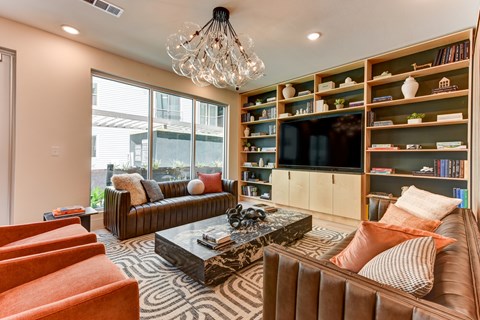 A living room with a brown couch, a coffee table, and a bookshelf with a flat screen TV on it.
