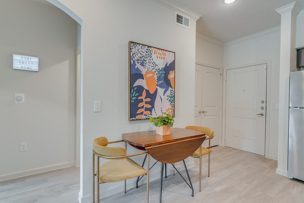 a dining room with a table and chairs and a painting on the wall