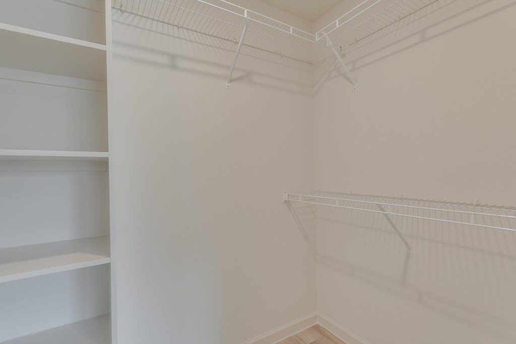 a walk in closet with white shelving and a white closet door