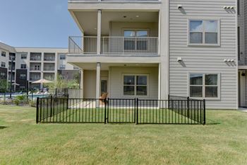 A grey apartment building with a black fence in front.