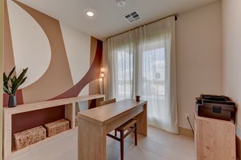 A room with a desk, chair, and a plant.