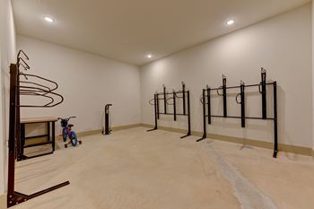 A room with a white wall and a wooden floor with a bicycle and a pull up bar.