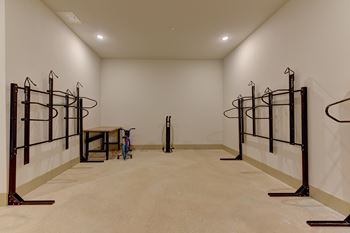 A room with a white wall and a brown floor with a table and a vacuum cleaner.