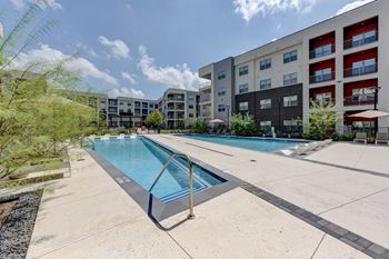 A swimming pool in a residential area with apartment buildings in the background.