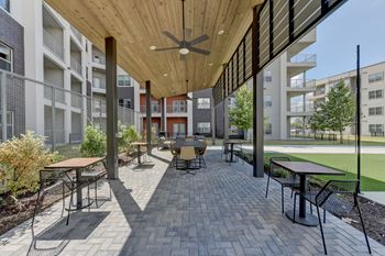 A patio with tables and chairs is surrounded by buildings.