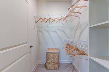 A white closet with a basket and hangers.