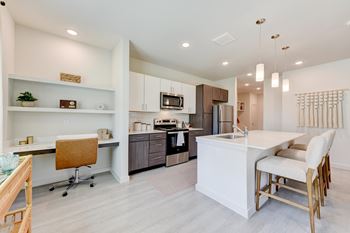 A modern kitchen with a white island and wooden chairs.