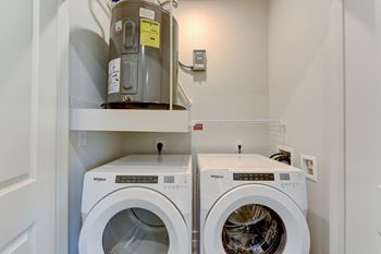 A washing machine is on top of a dryer in a small laundry room.
