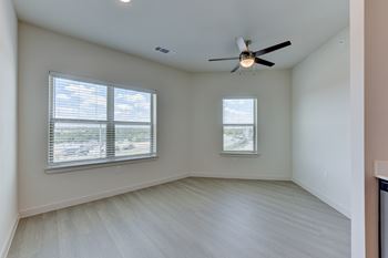 A room with a ceiling fan and two windows.