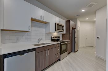 A modern kitchen with dark wood cabinets and stainless steel appliances.