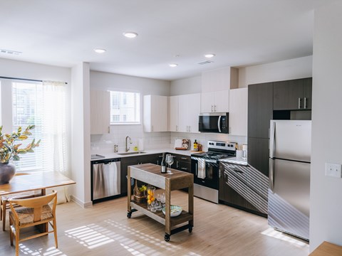 A modern kitchen with stainless steel appliances and wooden flooring.