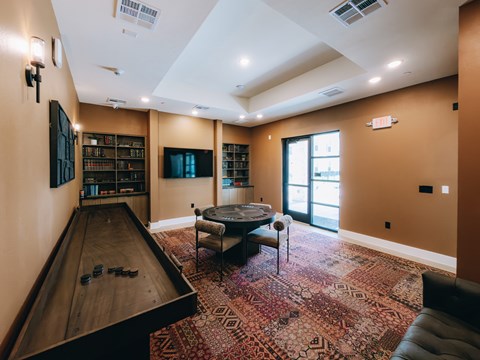 Shuffleboard and game lounge with bookshelves at Northwoods Apartments, Spring, 77388