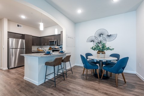 a kitchen and dining area with a table and chairs and a stainless steel refrigerator