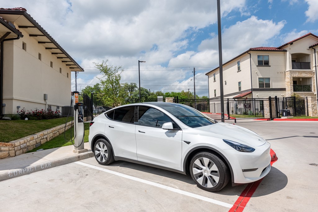 a white tesla parked at a charging station