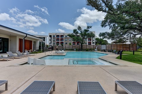 A swimming pool surrounded by lounge chairs and trees.