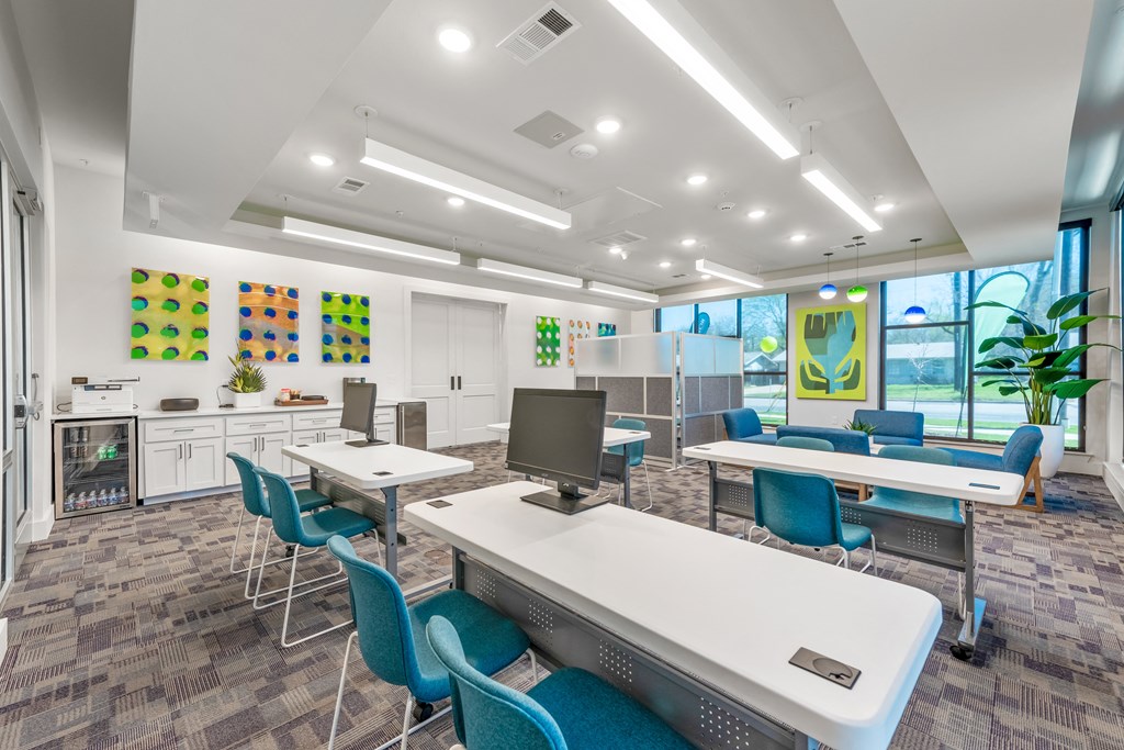 a computer lab with white tables and blue chairs