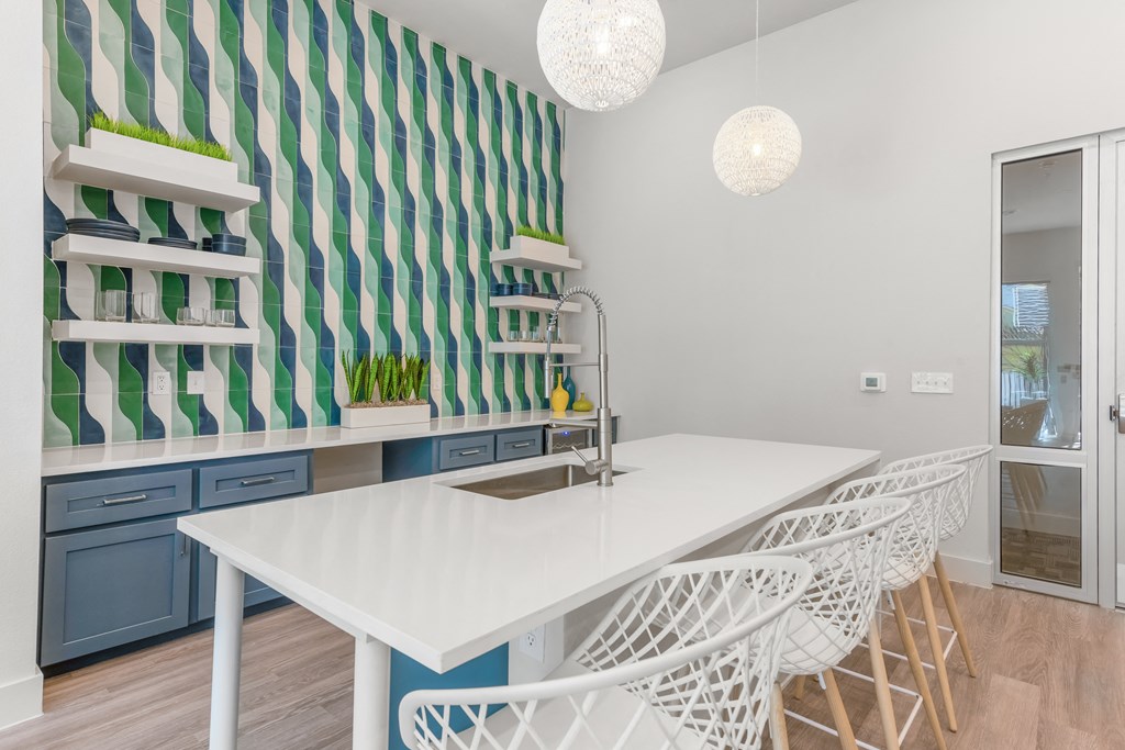 a kitchen with a white table and white chairs in front of a green and white striped wall