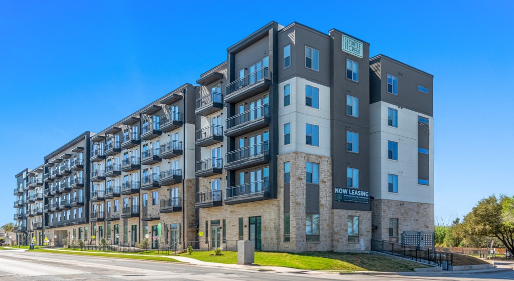 a large apartment building on a sunny day with a blue sky in the background
