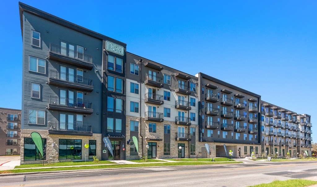 a large building with many balconies and a street in front of it