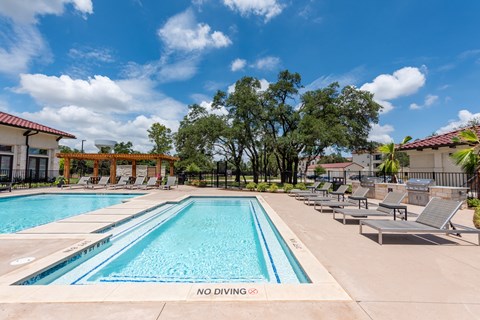 a swimming pool with lounge chairs and trees in the background at Avery Ranch, Austin Texas