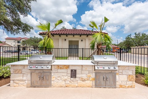 two bbq grills in front of a house with palm trees at Avery Ranch, Austin, Texas