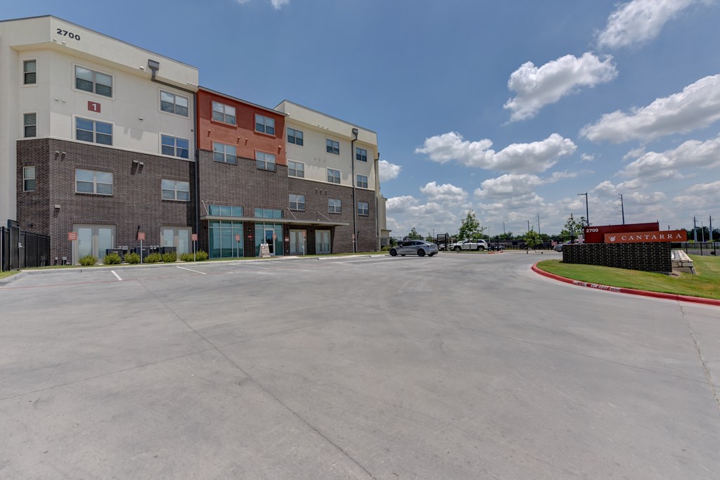 A parking lot in front of a multi-story apartment building.