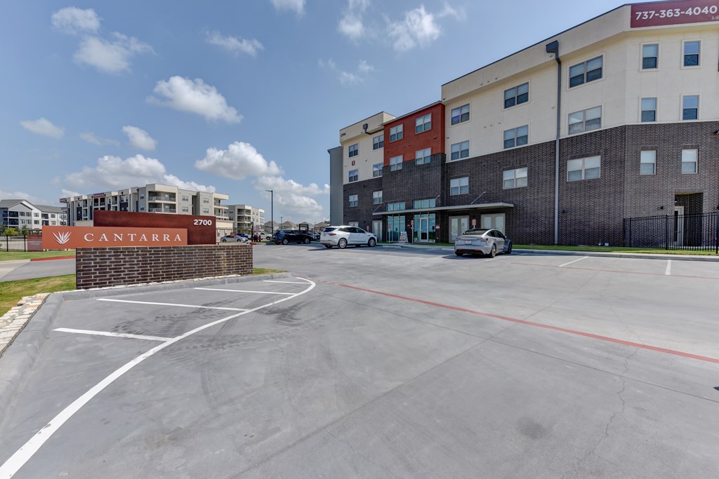 A parking lot in front of a multi-story building with a sign that reads "Cantara.".