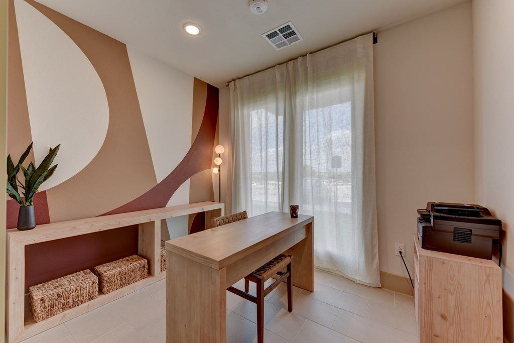 A room with a desk, chair, and a plant.