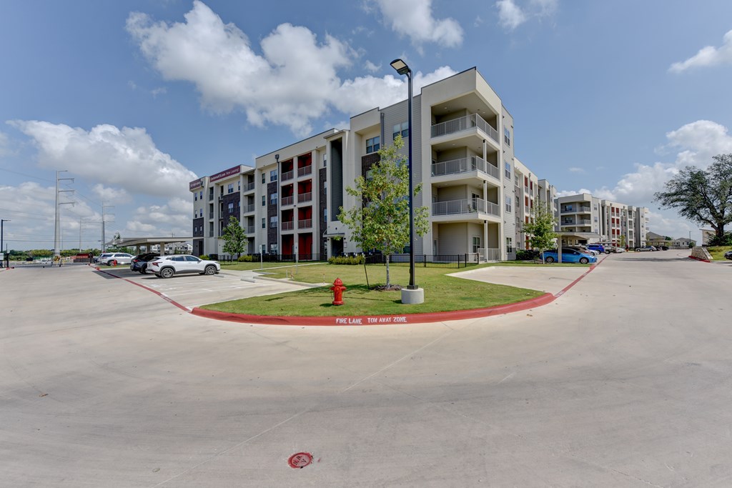 A parking lot in front of a multi-story apartment building.