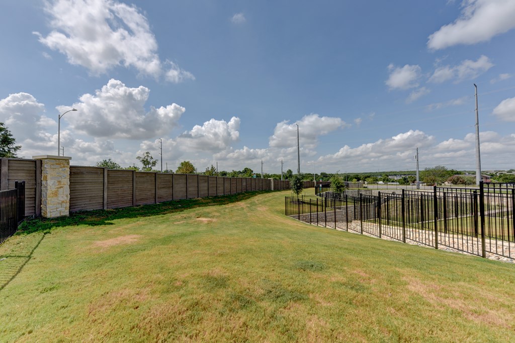 A long black fence runs along a grassy field.