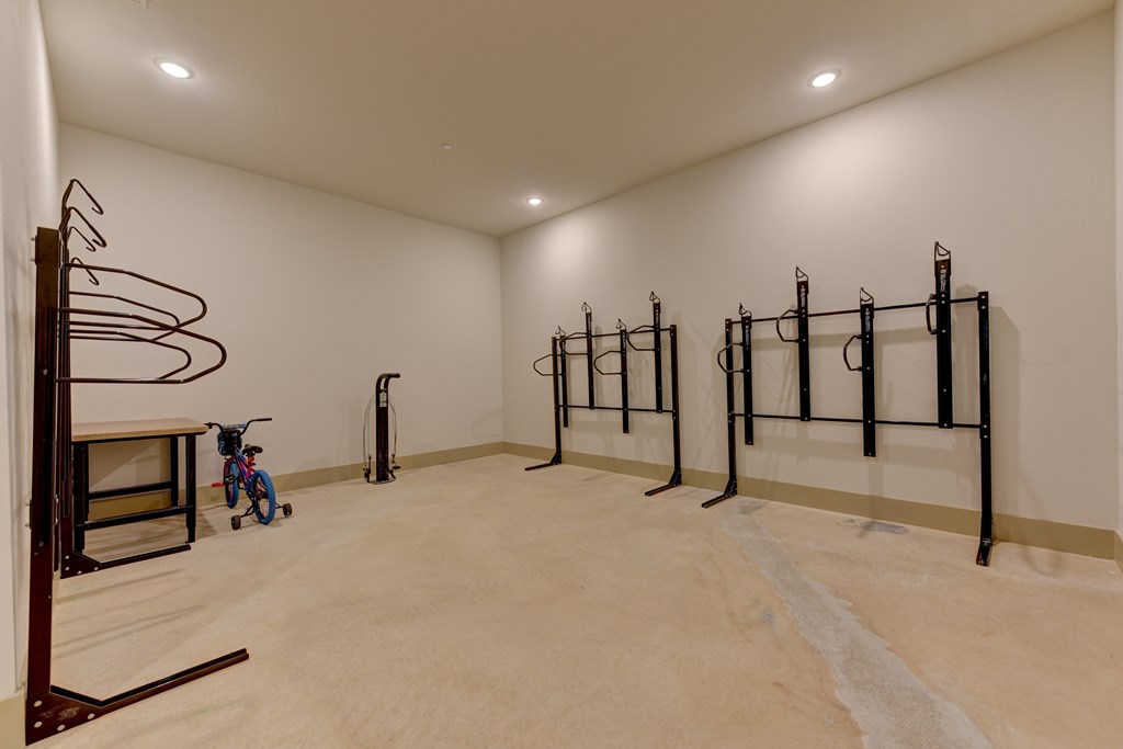 A room with a white wall and a wooden floor with a bicycle and a pull up bar.