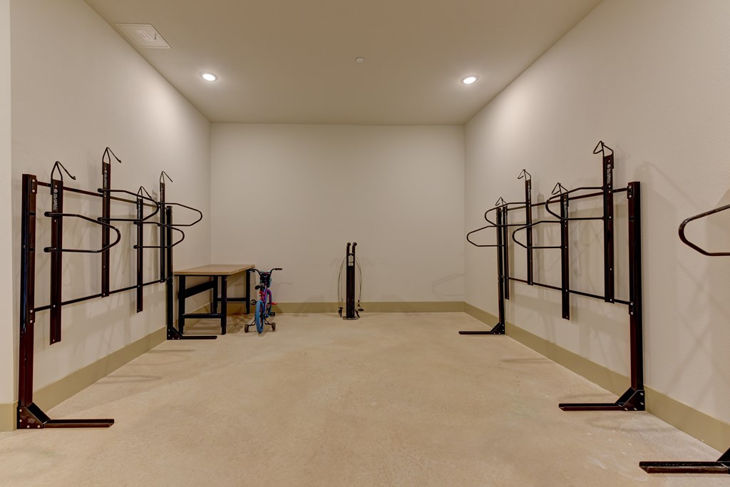 A room with a white wall and a brown floor with a table and a vacuum cleaner.