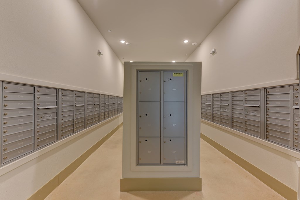 A long hallway with a row of mailboxes on the wall and a large mailbox in the middle.