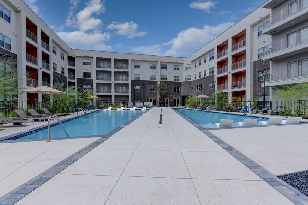 A large outdoor swimming pool surrounded by apartment buildings.