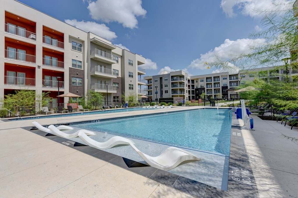 A large swimming pool in front of apartment buildings.