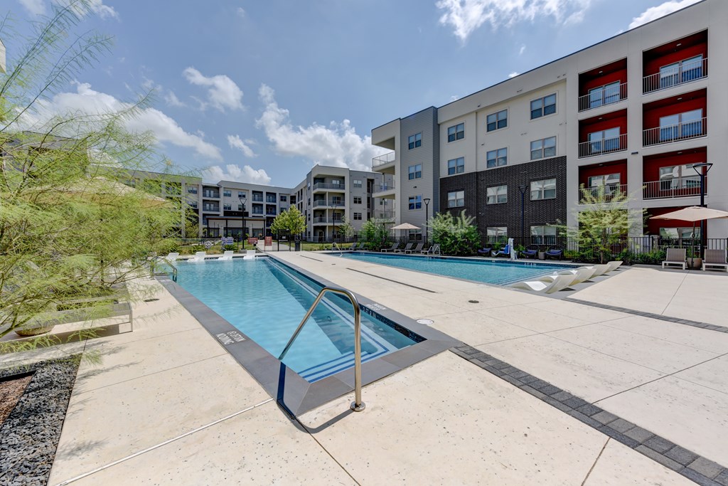 A swimming pool in a residential area with apartment buildings in the background.