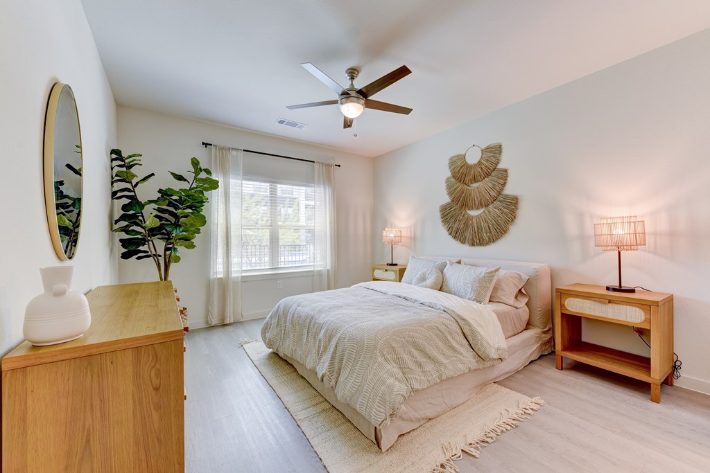 A bedroom with a bed, a wooden nightstand, and a wooden table with a lamp on it.