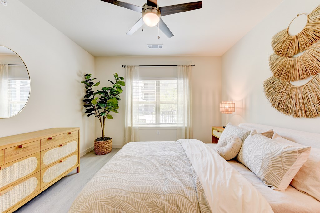 A bedroom with a large bed, a ceiling fan, and a wall-mounted lamp.