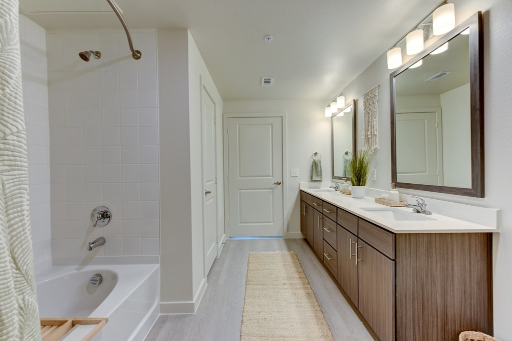 A bathroom with a white tub, sink, and mirror.