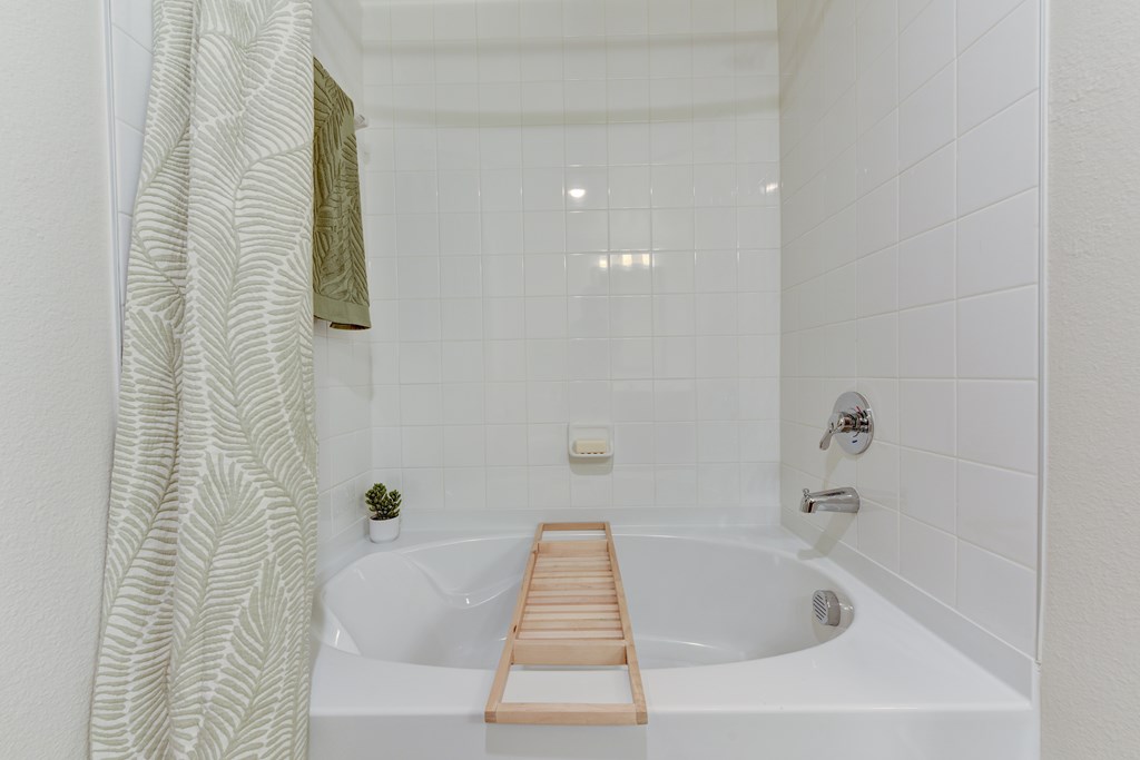 A white bathtub with a wooden seat in a bathroom.