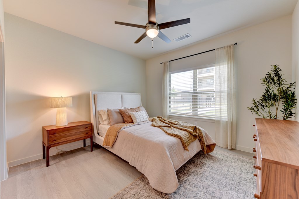 A bedroom with a bed, nightstand, and a ceiling fan.
