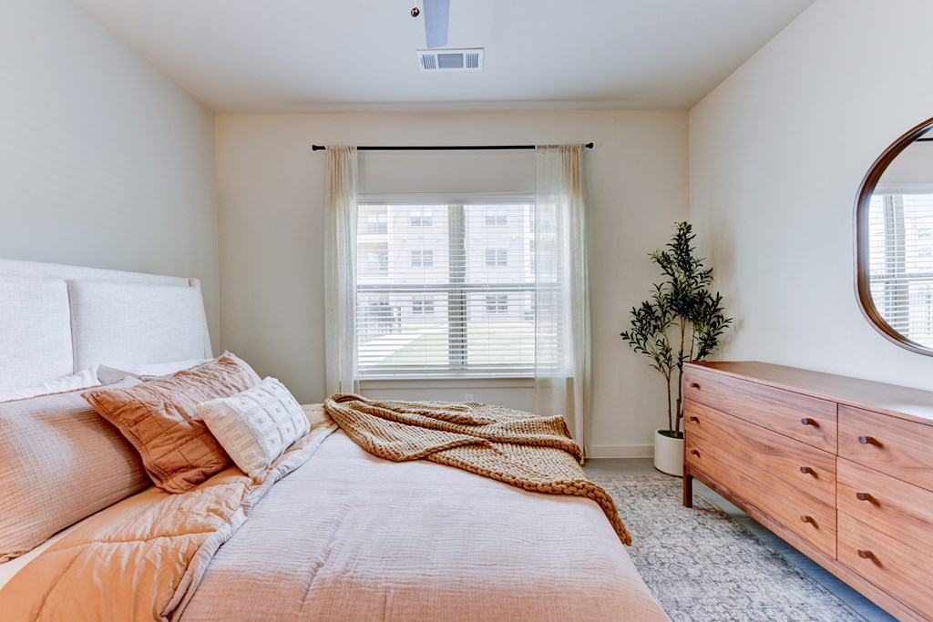 A bedroom with a bed, dresser, and window.