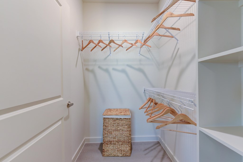 A white closet with a basket and hangers.